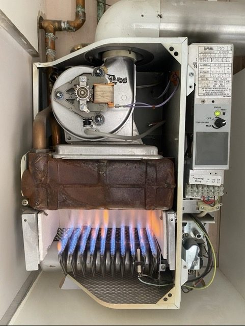Gas boiler opened up for servicing with the burner lit
